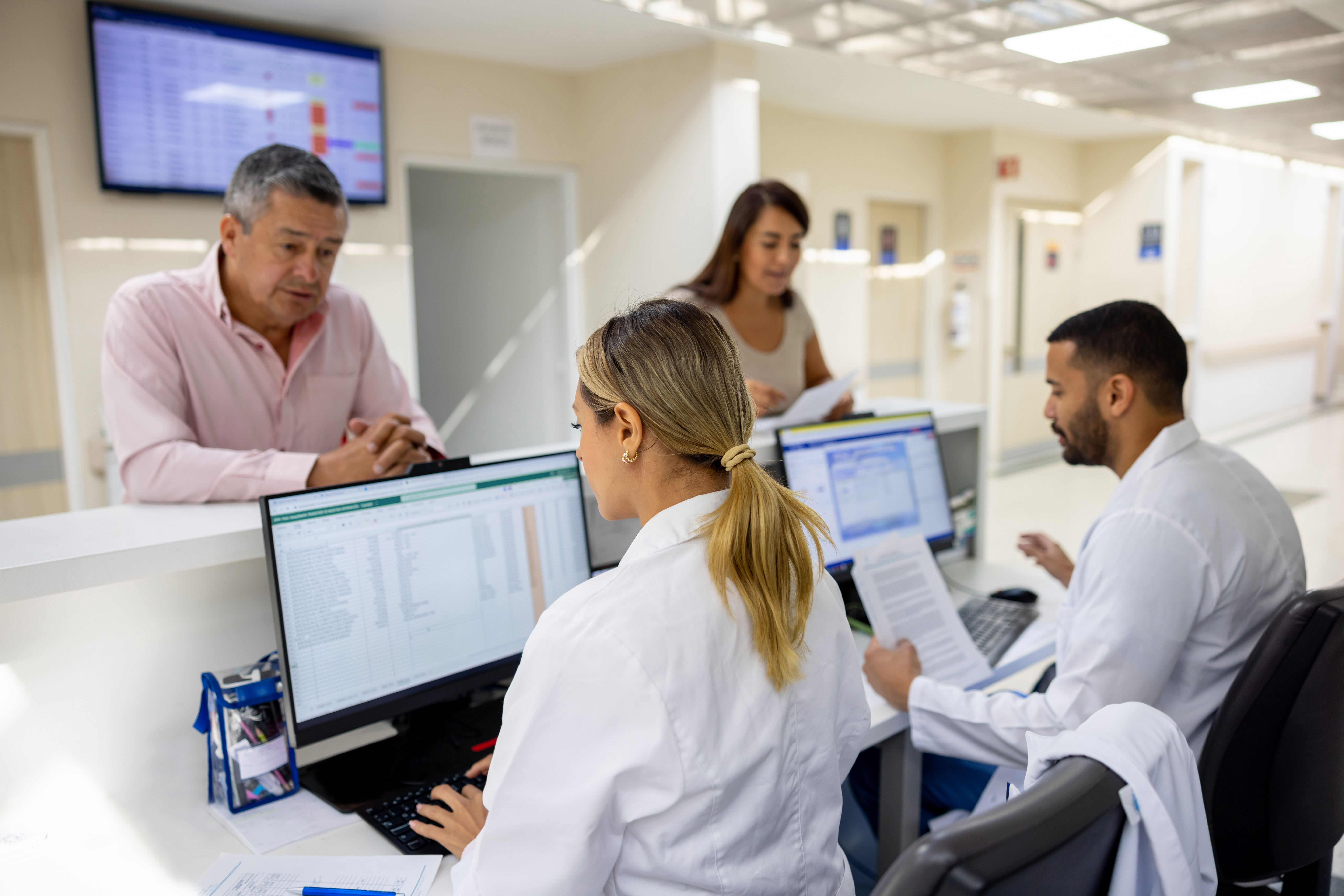 Latin American doctors registering patients at the hospital while working at the reception desk