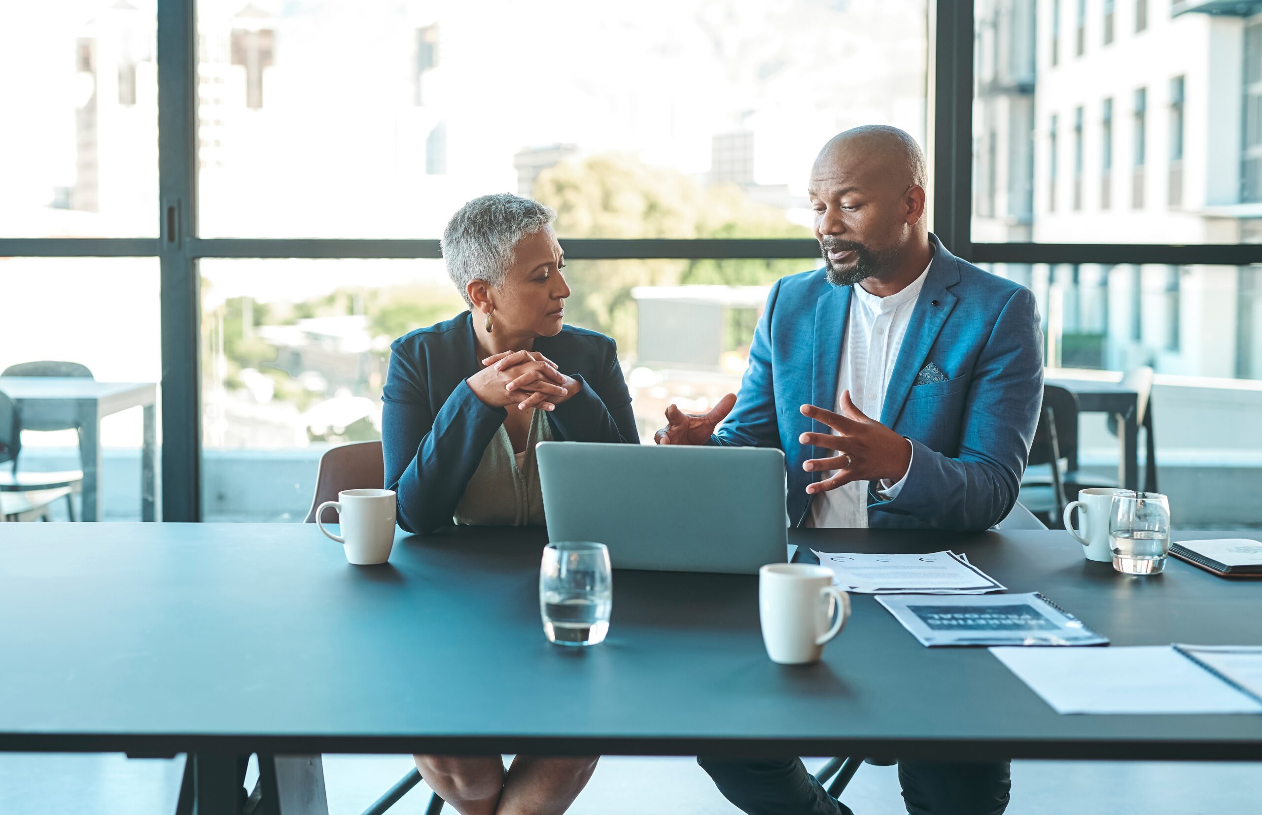 Business, presentation and man on a laptop in a corporate conference or office collaboration with a woman at work. Businessman, manager or coach for marketing, strategy and sales working with CEO.
